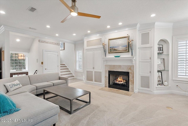 living room featuring crown molding, a fireplace with flush hearth, visible vents, and light colored carpet