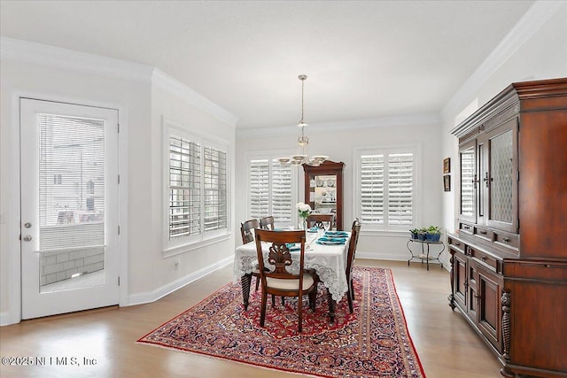 dining room featuring light wood-type flooring, plenty of natural light, and crown molding