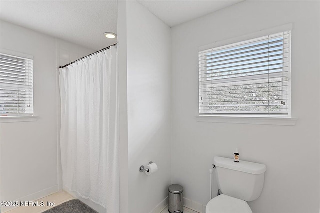 full bathroom with toilet, curtained shower, baseboards, and a textured ceiling