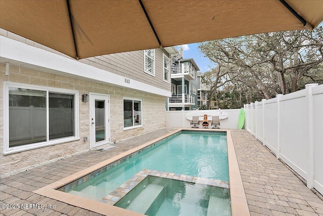 view of swimming pool with a fenced backyard and a pool with connected hot tub