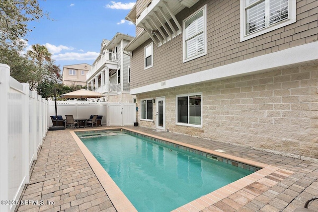 view of pool with a pool with connected hot tub, a fenced backyard, and a patio