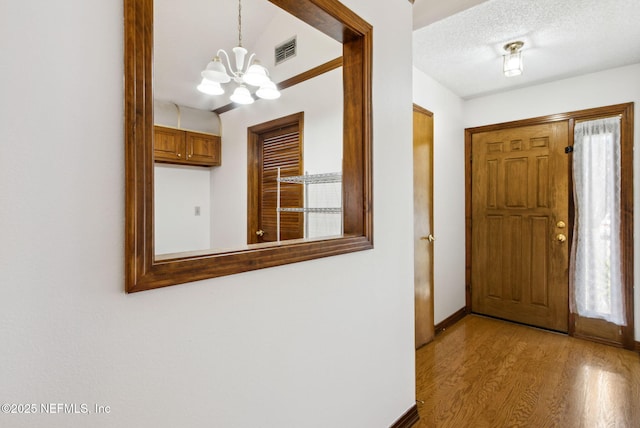 10800 Old St Augustine Rd Unit 301, Jacksonville, FL 32257 - entryway featuring light hardwood / wood-style flooring, a chandelier, and a textured ceiling