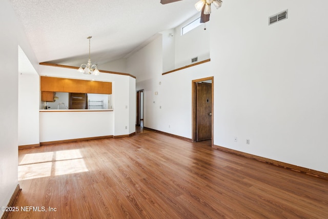 10800 Old St Augustine Rd Unit 301, Jacksonville, FL 32257 - unfurnished living room featuring sink, high vaulted ceiling, light hardwood / wood-style floors, a textured ceiling, and ceiling fan with notable chandelier