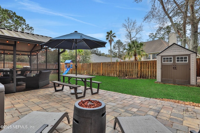 view of patio featuring a shed, a playground, and an outdoor fire pit