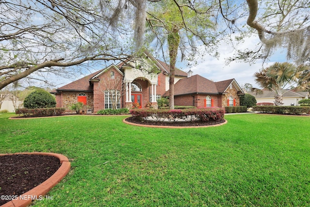 view of front of property featuring brick siding, roof with shingles, and a front yard