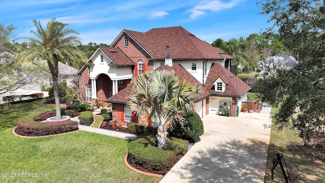 view of front of home with a shingled roof, brick siding, concrete driveway, stucco siding, and a front lawn