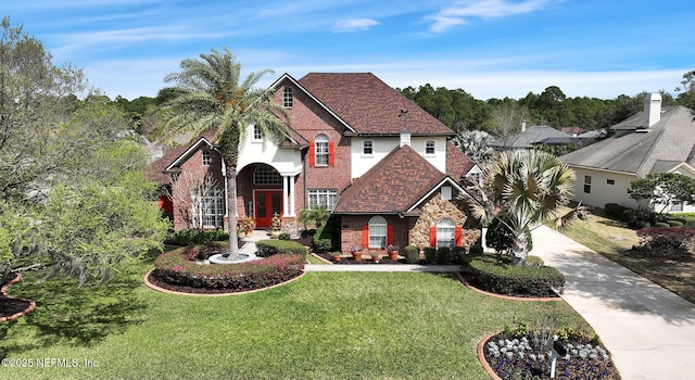 view of front facade with concrete driveway, a front lawn, roof with shingles, and brick siding