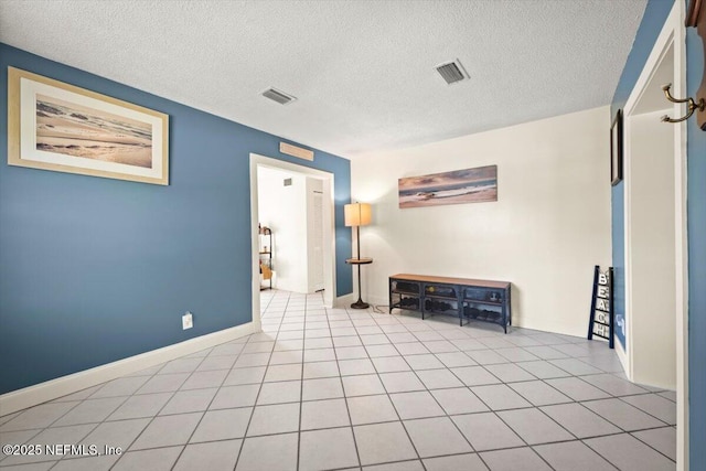 empty room featuring visible vents, a textured ceiling, and light tile patterned floors