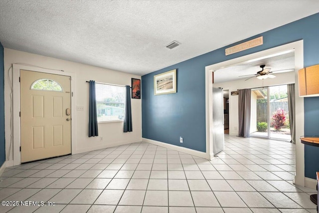 entryway with light tile patterned floors, baseboards, visible vents, a ceiling fan, and a textured ceiling