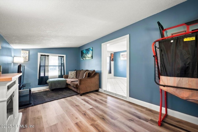 living area with light wood-style flooring, baseboards, and a textured ceiling