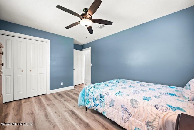 bedroom with light wood finished floors, a closet, visible vents, a ceiling fan, and baseboards