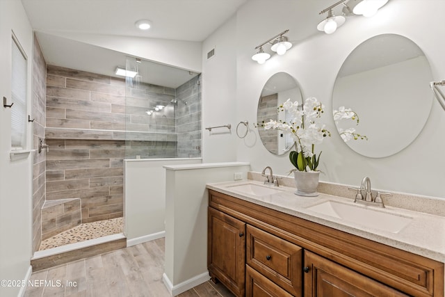 bathroom featuring wood-type flooring, vanity, and a tile shower