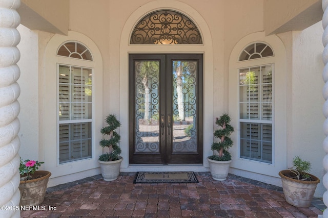 view of exterior entry with french doors and stucco siding