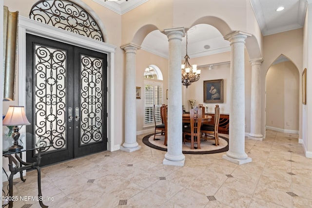 foyer entrance with arched walkways, french doors, crown molding, and ornate columns