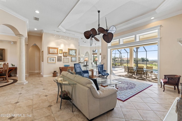 living room with arched walkways, a raised ceiling, visible vents, a ceiling fan, and ornate columns