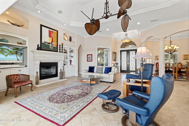 living area featuring arched walkways, a glass covered fireplace, french doors, ornate columns, and built in shelves