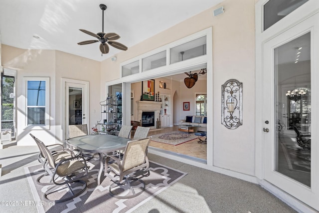 sunroom / solarium featuring ceiling fan with notable chandelier, a fireplace, and a healthy amount of sunlight