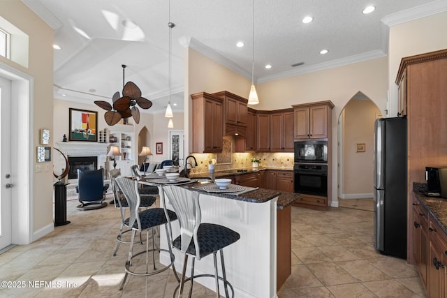 kitchen featuring a peninsula, black appliances, arched walkways, and a kitchen breakfast bar