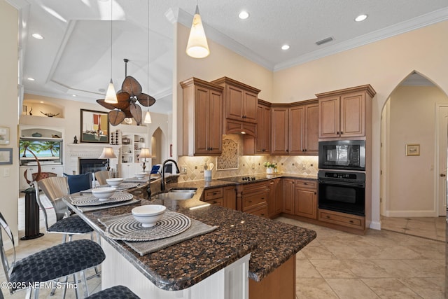 kitchen with black appliances, dark stone countertops, arched walkways, and a sink