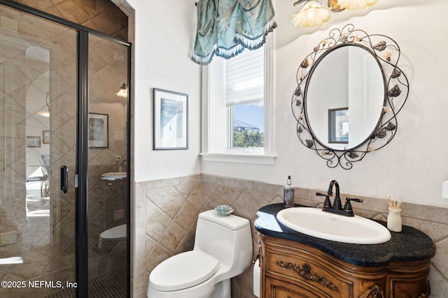 full bathroom featuring tile walls, toilet, a stall shower, wainscoting, and vanity