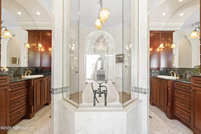 bathroom with a shower stall, ornamental molding, and two vanities