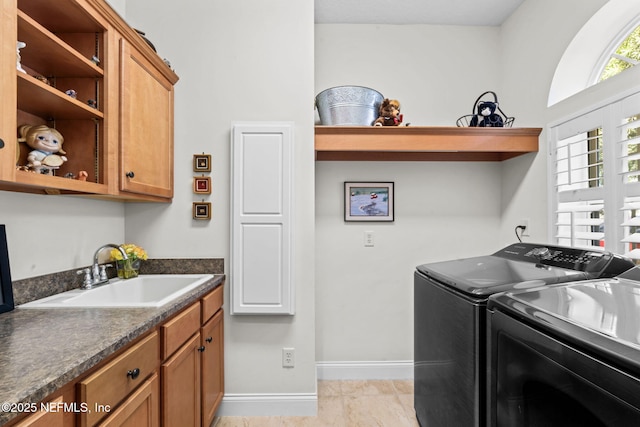 laundry area featuring independent washer and dryer, a sink, cabinet space, and baseboards