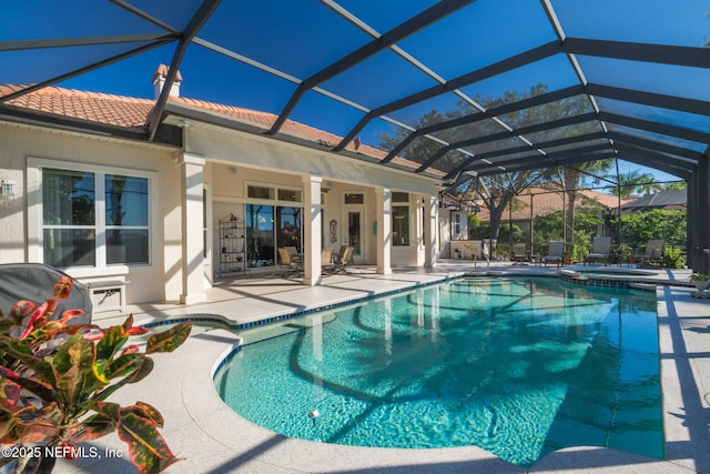 view of swimming pool with a patio, glass enclosure, and a pool with connected hot tub