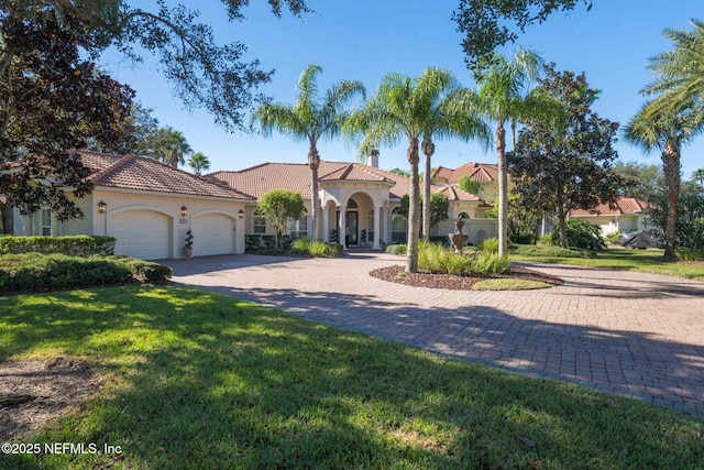 mediterranean / spanish house with a garage, a front yard, decorative driveway, and stucco siding