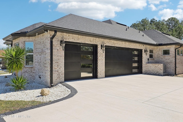 view of side of property with a garage, roof with shingles, and brick siding