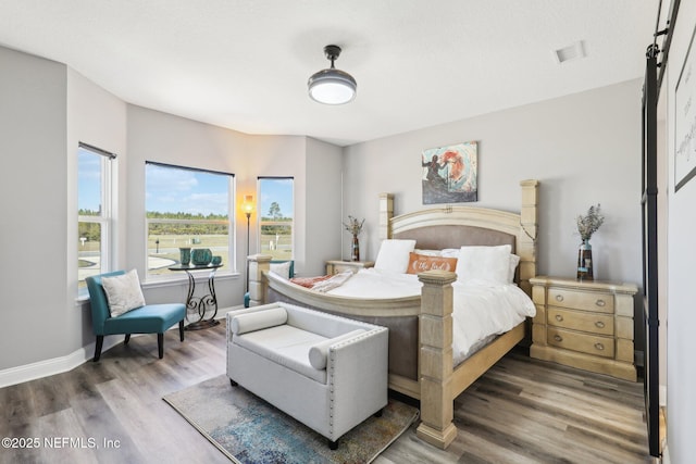 bedroom featuring wood finished floors, visible vents, and baseboards