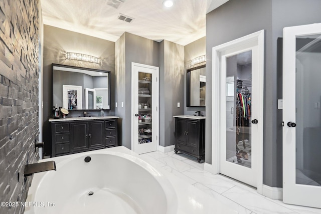 full bath featuring marble finish floor, visible vents, a spacious closet, vanity, and a bath