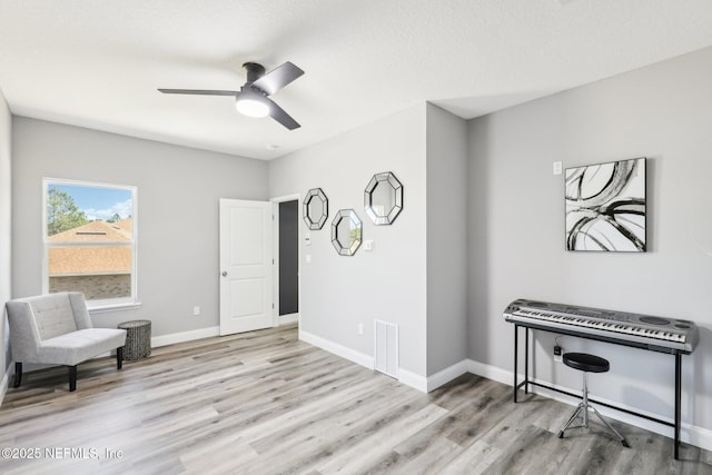 living area with visible vents, ceiling fan, baseboards, and wood finished floors