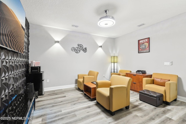 living area with light wood-style floors, baseboards, and visible vents