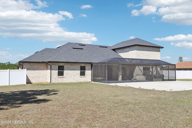 back of house with glass enclosure, fence, driveway, a lawn, and a patio area