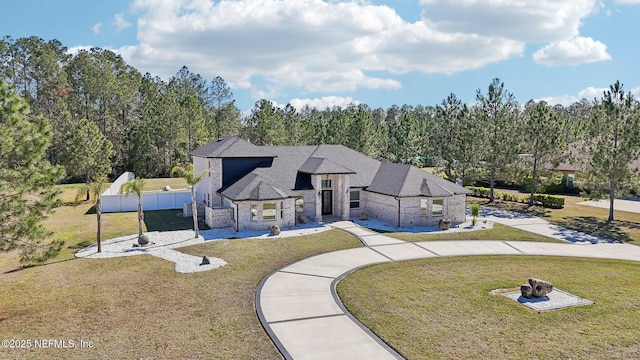 view of front of house with roof with shingles, a front lawn, an outdoor fire pit, and fence