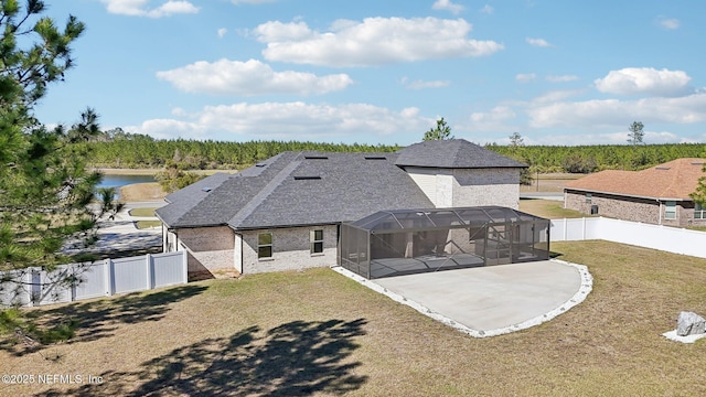 back of property with a lawn, a fenced backyard, roof with shingles, a lanai, and brick siding