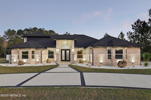 prairie-style home with french doors, brick siding, and roof with shingles