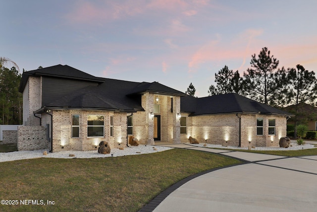 view of front of house with brick siding, concrete driveway, and a yard