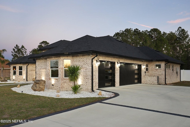 view of front of property with a garage, brick siding, a shingled roof, driveway, and a front yard