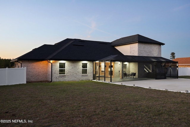 back of house with brick siding, a lawn, a patio area, and fence