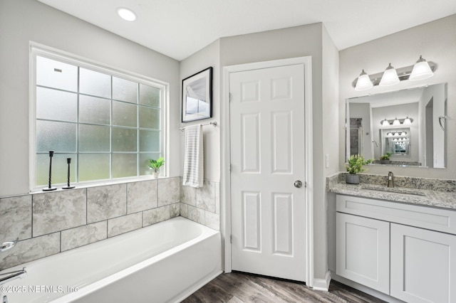 bathroom with wood-type flooring, a bath, and vanity