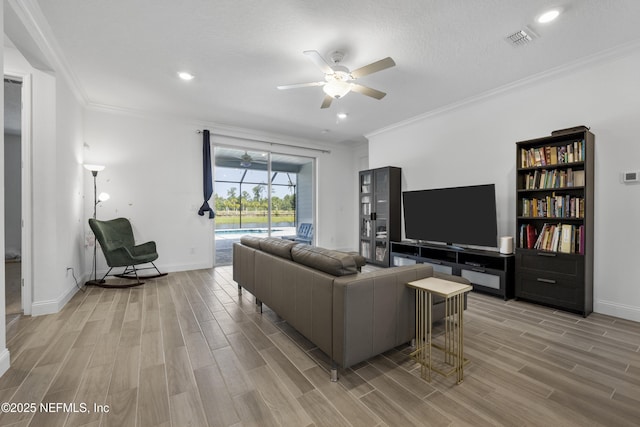 living room with ceiling fan, ornamental molding, and a textured ceiling