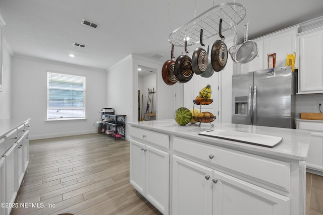 kitchen with white cabinetry, stainless steel fridge, light hardwood / wood-style floors, and a kitchen island