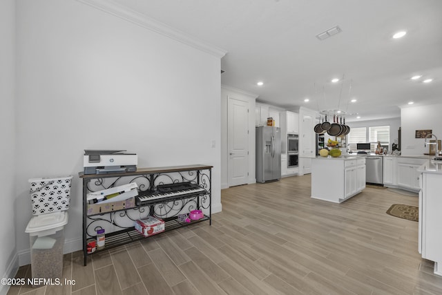 kitchen with appliances with stainless steel finishes, white cabinetry, a center island, kitchen peninsula, and light wood-type flooring