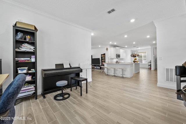 interior space with ornamental molding, sink, and light hardwood / wood-style flooring