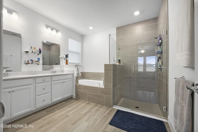 bathroom featuring vanity, a textured ceiling, and separate shower and tub