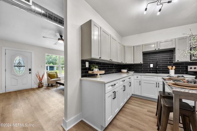 kitchen featuring white cabinetry, backsplash, light hardwood / wood-style floors, and ceiling fan