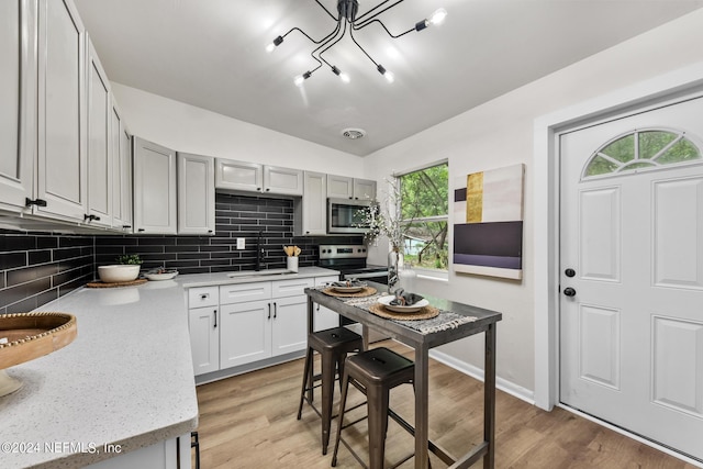 kitchen featuring sink, light stone counters, light hardwood / wood-style flooring, decorative backsplash, and white cabinets