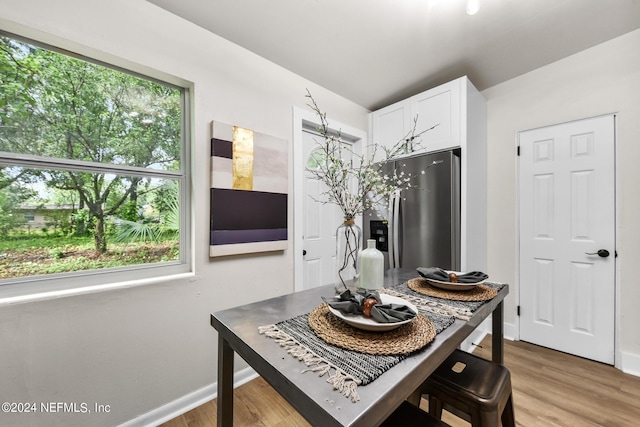 kitchen with a healthy amount of sunlight, stainless steel fridge, light hardwood / wood-style floors, and white cabinets