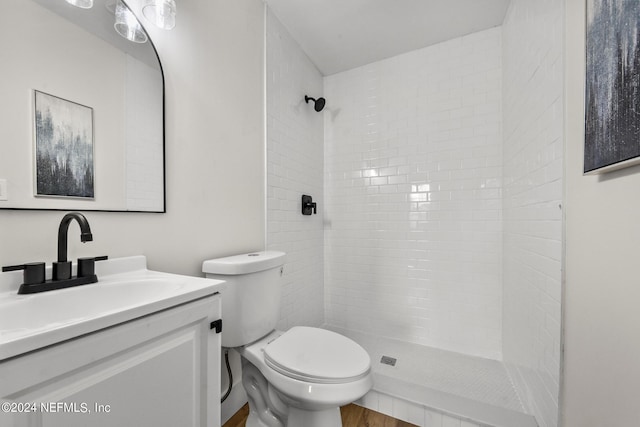 bathroom featuring vanity, toilet, and a tile shower